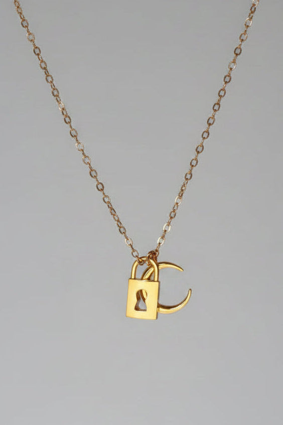 A delicate rose gold chain necklace with a small padlock pendant featuring an integrated 'C' charm, displayed against a draped white satin fabric background.