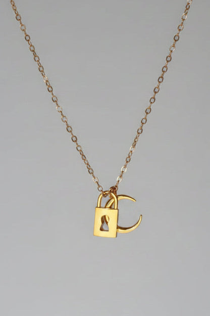 A delicate rose gold chain necklace with a small padlock pendant featuring an integrated 'C' charm, displayed against a draped white satin fabric background.