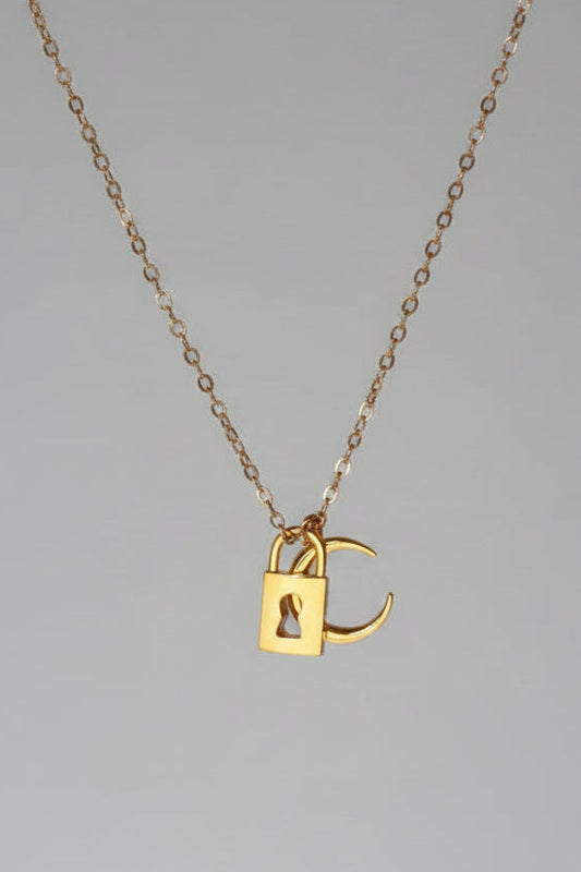 A delicate rose gold chain necklace with a small padlock pendant featuring an integrated 'C' charm, displayed against a draped white satin fabric background.
