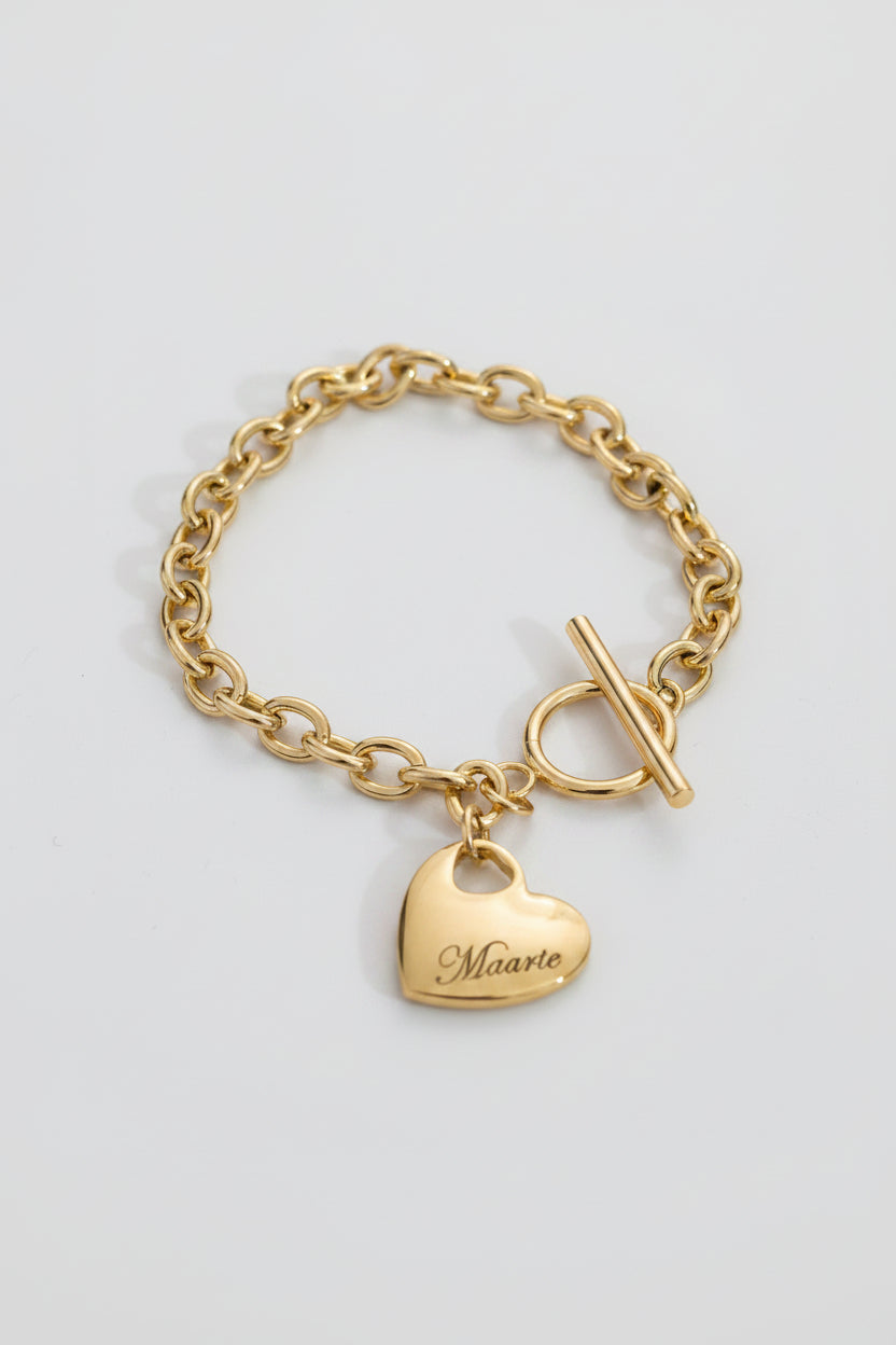 Gold chain bracelet with a heart-shaped tag on a black background