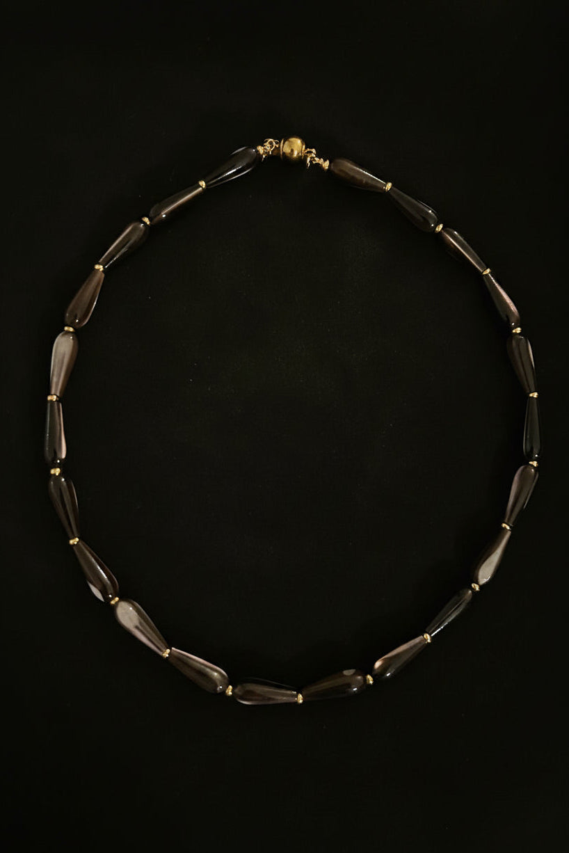 Necklace with dark beads and gold accents on a black background